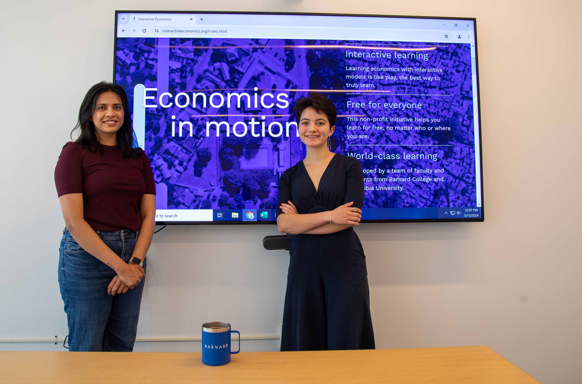 Two young women standing in front of a screen with blue background